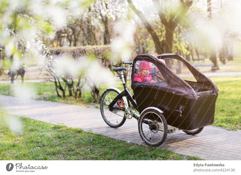 Children having a ride in a cargo bike during spring tricycle day healthy lifestyle active outdoors fun joy park bicycle biking activity cyclist enjoying