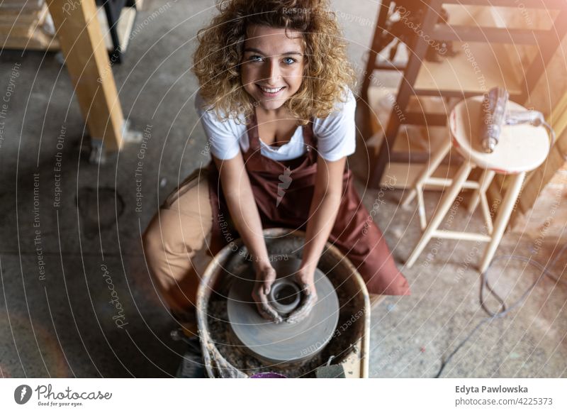 Woman making ceramic work with potter's wheel pottery artist ceramics working people woman young adult casual attractive female happy Caucasian enjoying