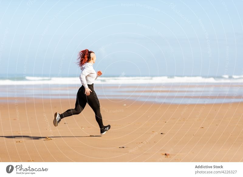 Fast runner jogging on sandy sea beach during workout jogger seashore sport training cardio activity woman sportswoman exercise fast motion endurance motivation