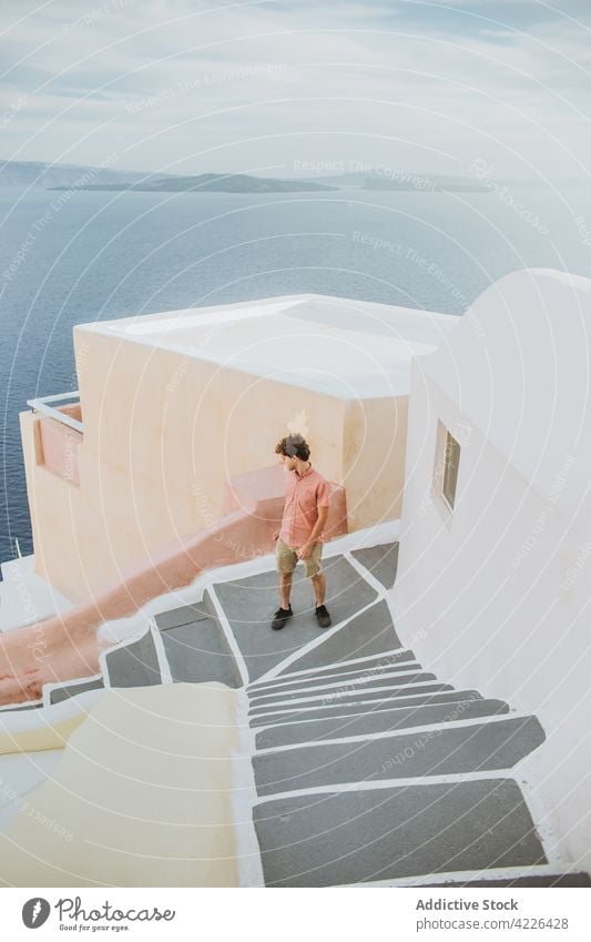 Unrecognizable man standing on stone staircase in coastal village sea town oia village step architecture seacoast tourist weathered aged santorini greece female