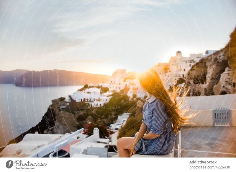 Anonymous tourist contemplating old village under cloudy sky contemplate architecture neighborhood travel windy woman weather flying hair traveler atmosphere