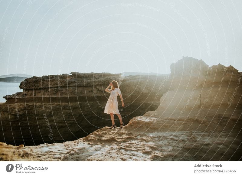 Faceless woman standing on rocky seacoast grace cliff seafront seashore nature travel resort coastline sarakiniko milos greece figure feminine tranquil gorgeous