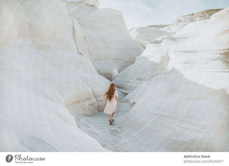 Unrecognizable woman walking along rocky curvy formations stroll geology stony passage nature stone path rough sarakiniko milos greece narrow sunlight white