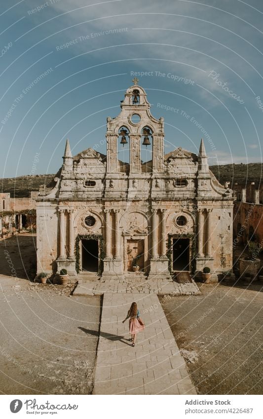 Faceless woman walking towards medieval temple facade architecture historic heritage sightseeing exterior landmark stroll attraction arkadi monastery remain