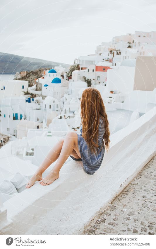 Anonymous tourist contemplating old village under cloudy sky contemplate architecture neighborhood travel windy woman weather flying hair traveler atmosphere