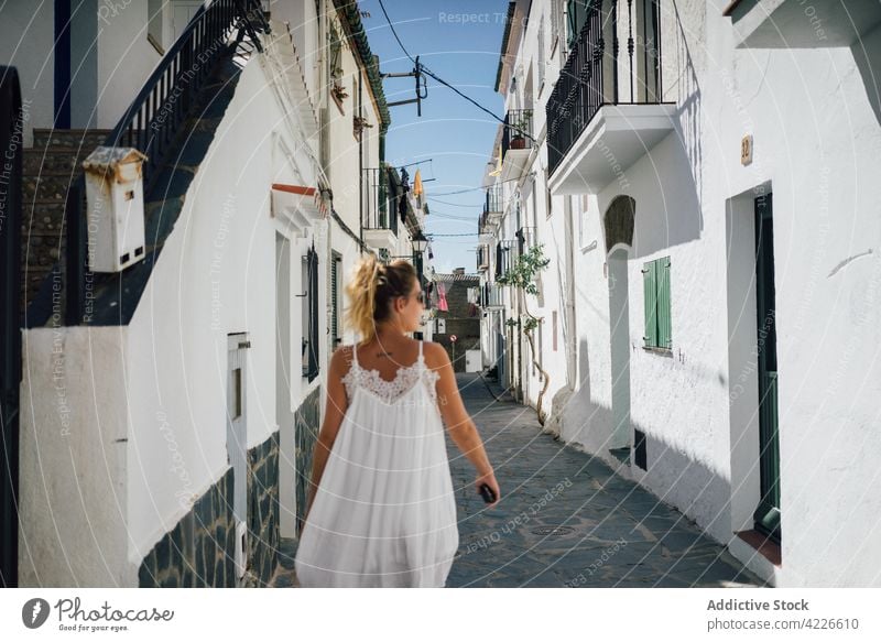 Traveler in white dress on urban street between old houses traveler architecture building trip feminine vacation woman city dwell straight walkway idyllic alone