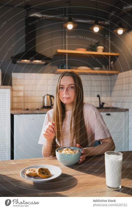 Woman eating delicious cereal for breakfast at home woman corn ring sweet nutrition portrait kitchen portion table domestic spoon bowl enjoy millennial friendly