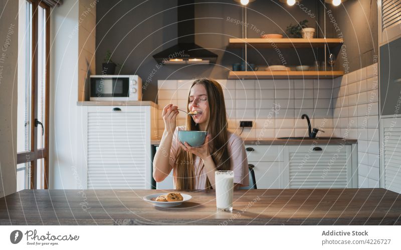 Woman eating delicious cereal for breakfast at home woman corn ring sweet nutrition mouth opened portrait kitchen portion table domestic spoon bowl enjoy