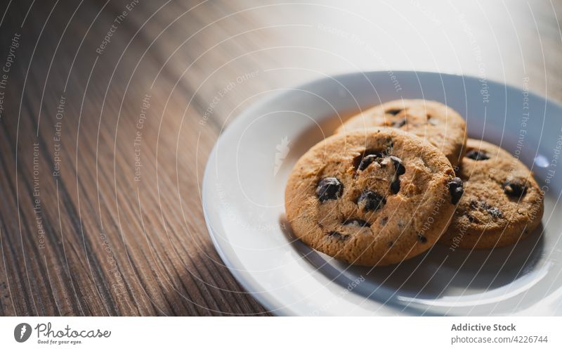 Delicious oat cookies for breakfast sweet treat dairy chocolate chip nutrient table plate oatmeal baked biscuit domestic desk wooden ceramic material round