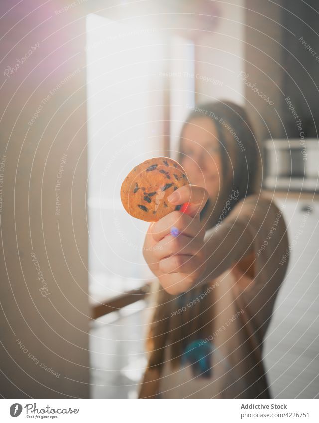 Woman with tasty oat biscuit in house kitchen in sunshine woman cookie oatmeal treat sweet chocolate chip baked breakfast home shiny show outstretch idyllic