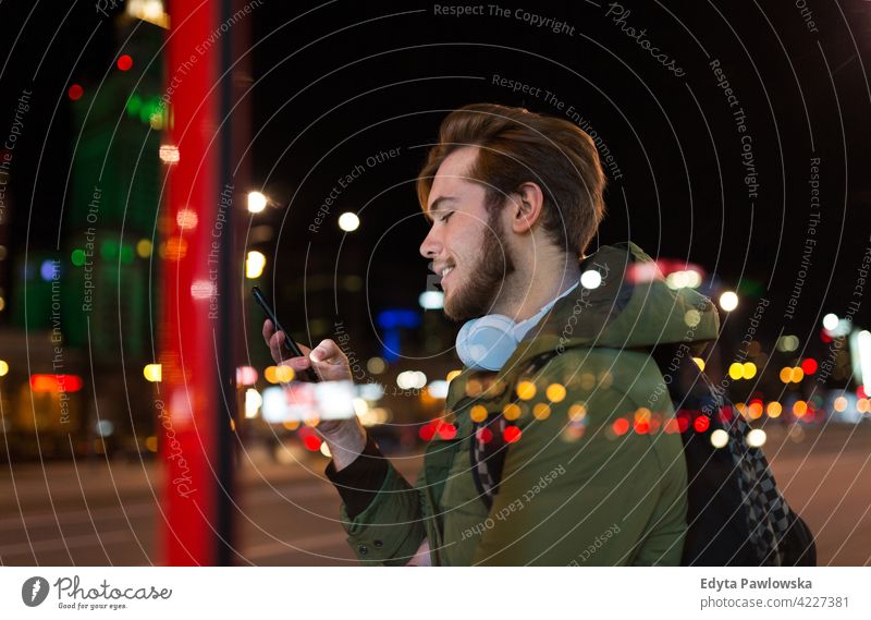 Young man using smartphone on urban street at night male boy student tourist city people young adult casual Caucasian enjoying one person confident dusk evening