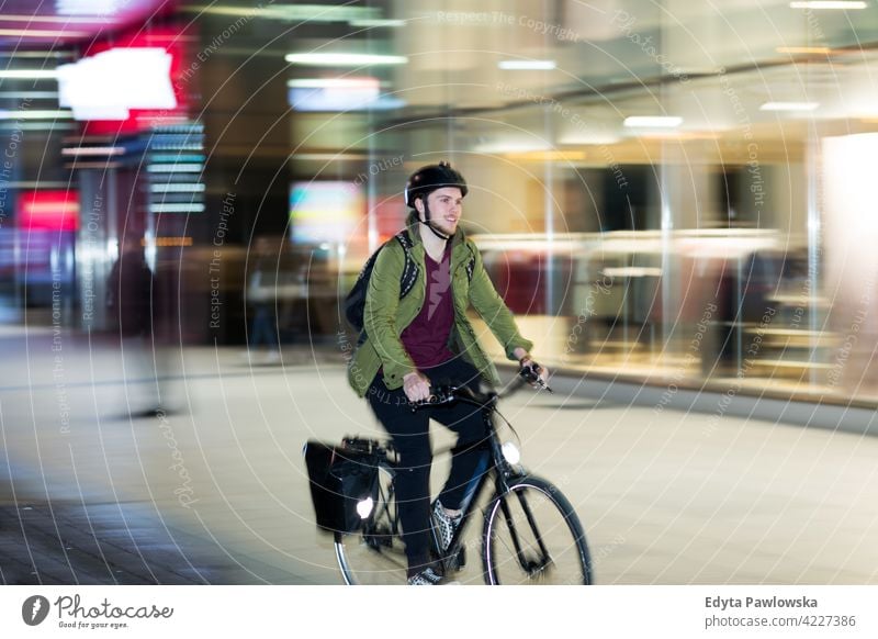 Young man on bicycle in the city at night male boy student tourist urban street people young adult casual Caucasian enjoying one person confident dusk evening