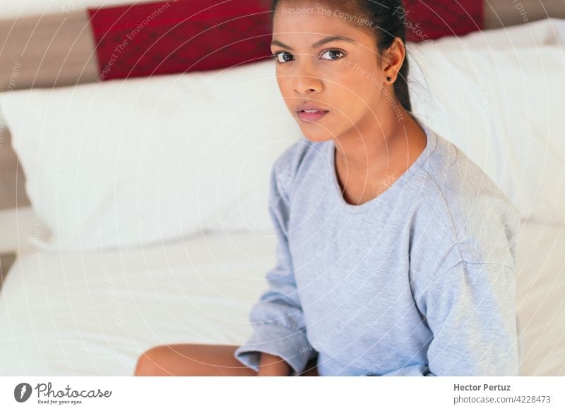 An attractive young woman sits on her bedroom bed. She looks at the camera black african happy portrait relaxation people beauty women home adult comfortable