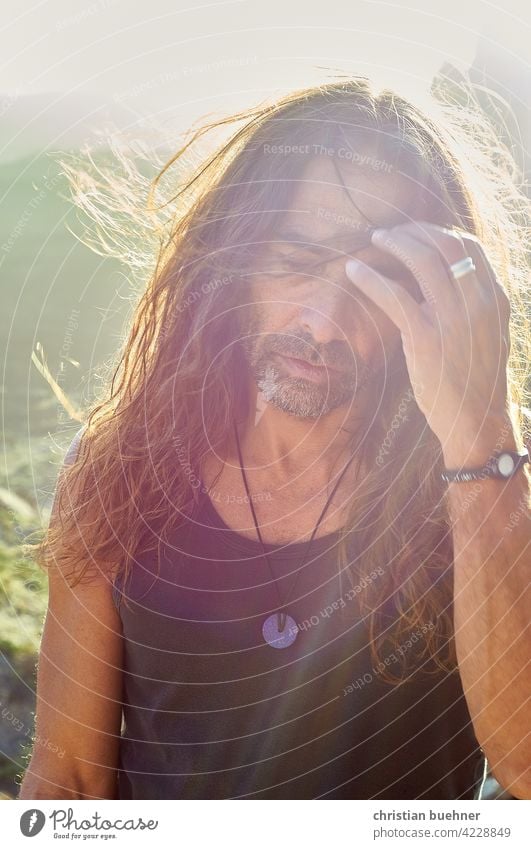 older hippie in the sunset Man portrait 50 years Hippie Sun Summer long hairs Alternative young-at-heart vacation Meditative Back-light Sunset Meditation spirit