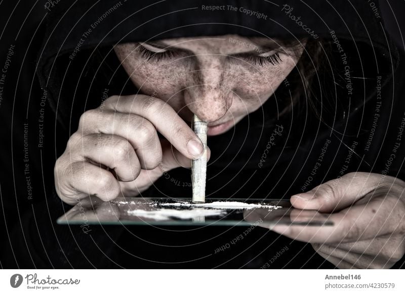 Drug Addict sniffing and snorting Cocaine,speed, Heroin or other drug with money rolled up on mirror with dark background, addiction,drugs,depressed concept