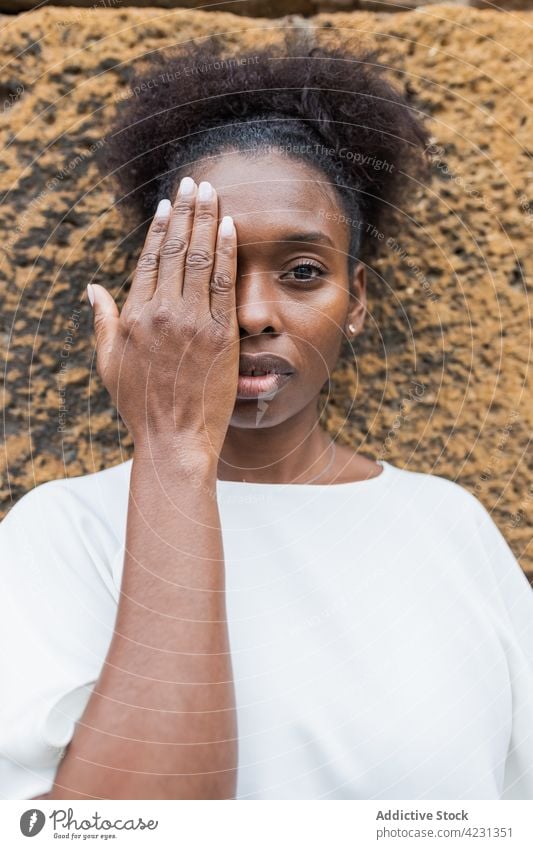 Unemotional black woman covering half face with hand hide cover face cover eyes glance calm emotionless posture appearance individuality personality casual