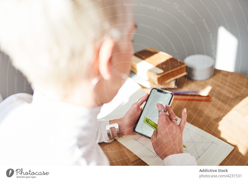 Astrologer with smartphone in house on sunny day astrologer attentive internet online pastime reflection woman portrait using gadget device home cellphone