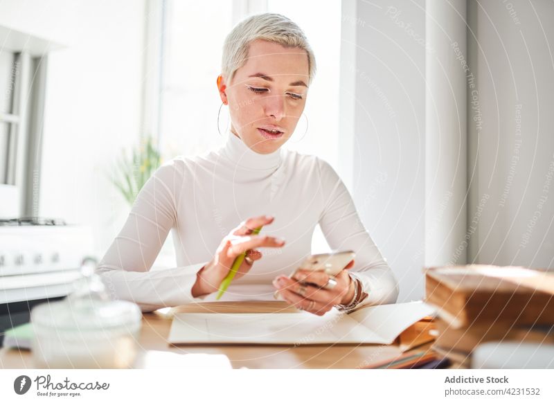 Astrologer with smartphone in house on sunny day astrologer attentive internet online pastime reflection woman portrait using gadget device home cellphone