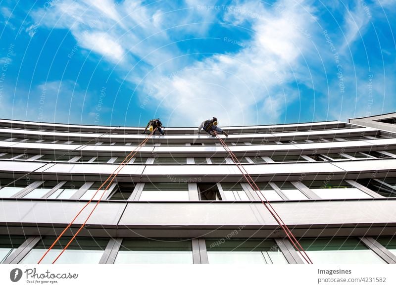 Window washers! Two male industrial climbers cleaning windows on a building. high in the air against blue cloudy sky window cleaner two masculine Industrial