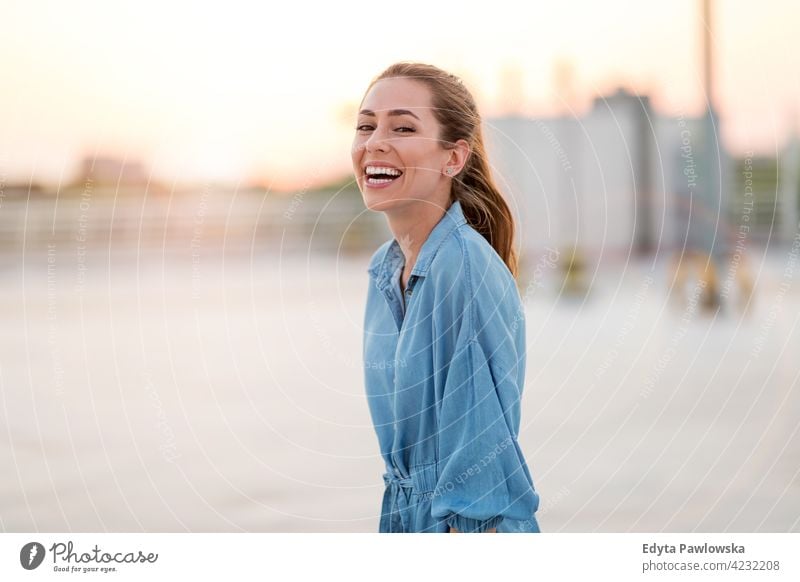 Portrait of an young woman on a rooftop enjoying sunset confident smiling female attractive beautiful young adult positive content standing lifestyle happy