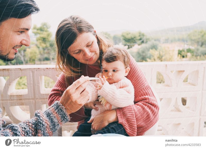 Real family sharing the first food of their baby real eating together complementary feeding mom dad childcare puree cream outdoors babyhood parenthood