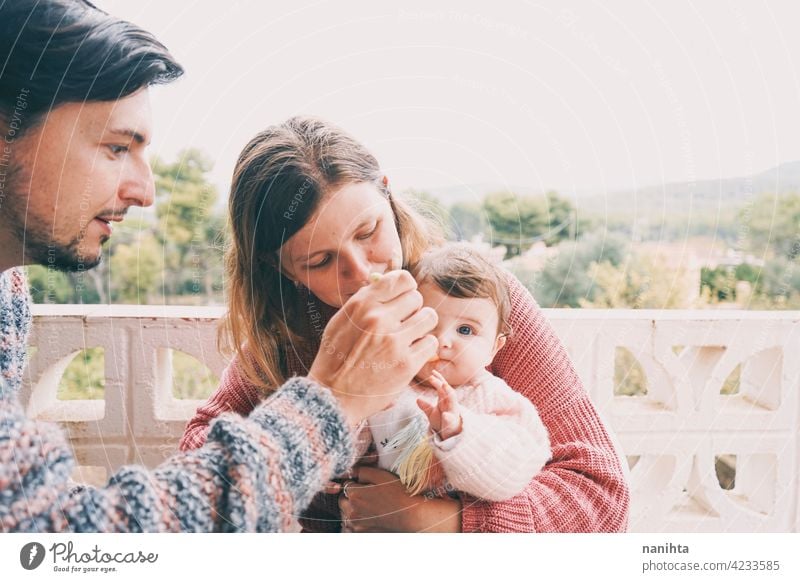 Real family sharing the first food of their baby real eating together complementary feeding mom dad childcare puree cream outdoors babyhood parenthood