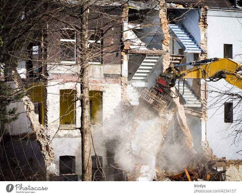 Demolition excavator at work. Demolition of a row of houses, demolition work of residential buildings, dust development Building for demolition