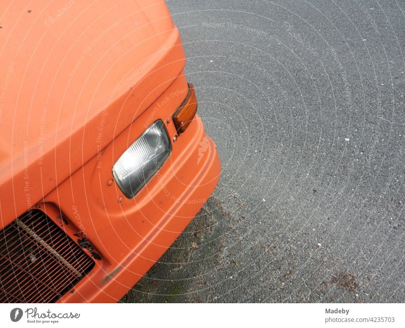 Former parcel car converted to a camper van in matt bright orange on a rain-soaked road in Oerlinghausen near Bielefeld in the Teutoburg Forest in East Westphalia-Lippe