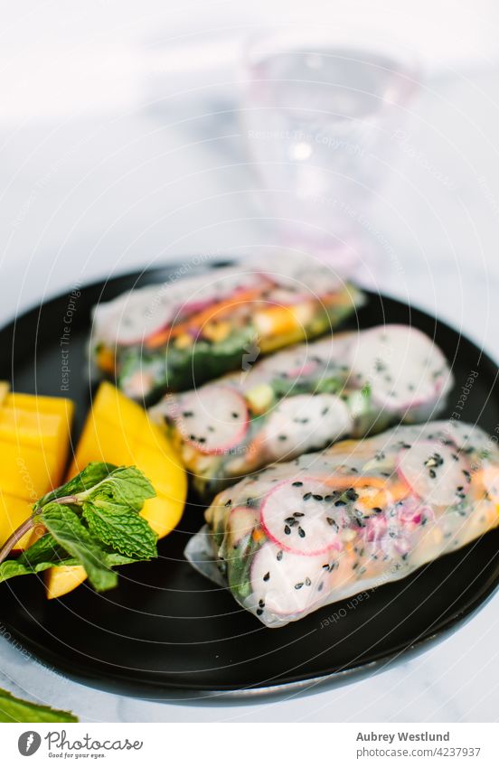 Colorful Viatnamese spring rolls with black sesame seeds, and mango on a black plate Asia Vietnam Vietnamese Vietnamese food appetizer asian avocado background