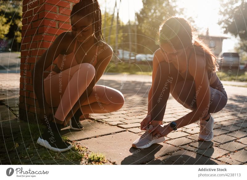 Multiracial sportswomen putting on sneakers before working out in town put on tie prepare body fit pavement friendship multiracial african american black