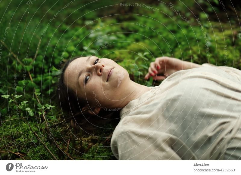 Young woman lying on moss in forest clearing Woman Moss Forest Ground Woodground pretty Graceful Brunette 18 - 30 years 30 - 45 years Long-haired Dress plants