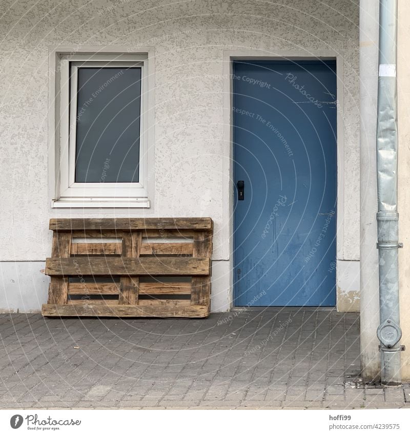 Window and blue door with pallet and dented drainpipe Dented Downspout Backyard dreariness Wall (building) remnants Interior courtyard idyllic backyard