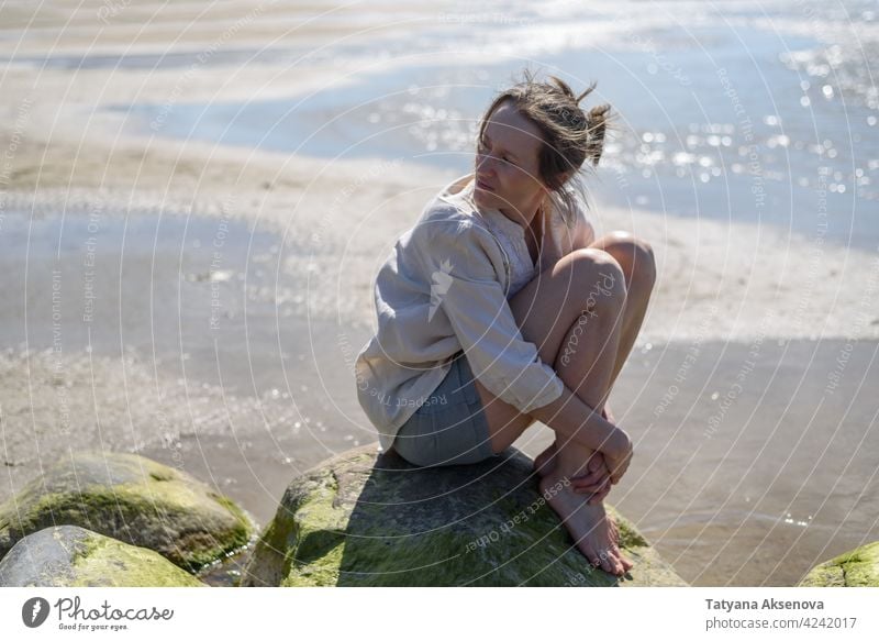 Woman sitting near sea, looking to water woman nature outdoor wellbeing relaxation mindfulness breathing tranquility meditation person freedom lifestyle summer