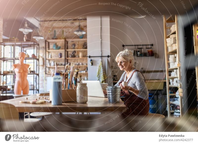 Senior craftswoman in art studio pottery artist ceramics work working people senior adult casual attractive female happy Caucasian enjoying one person beautiful