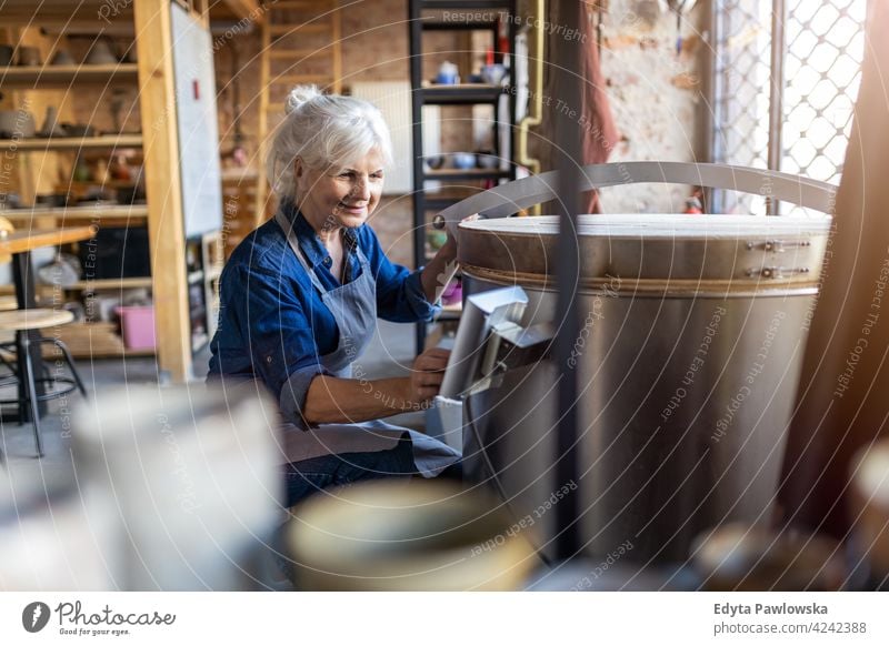 Portrait of senior female pottery artist in her art studio ceramics work working people woman adult casual attractive happy Caucasian enjoying one person