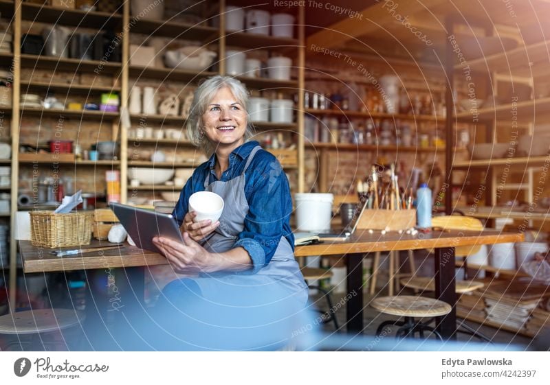 Portrait of senior female pottery artist in her art studio ceramics work working people woman adult casual attractive happy Caucasian enjoying one person