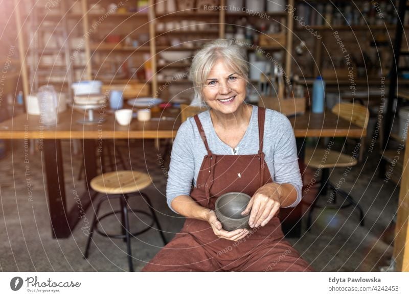 Portrait of senior female pottery artist in her art studio ceramics work working people woman adult casual attractive happy Caucasian enjoying one person