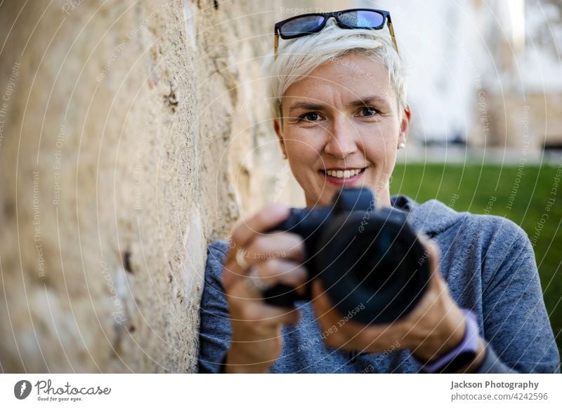 Smiling woman with the digital camera in her hands portrait photographer smile old copy space hoody female glasses positive girl photographer take a photo