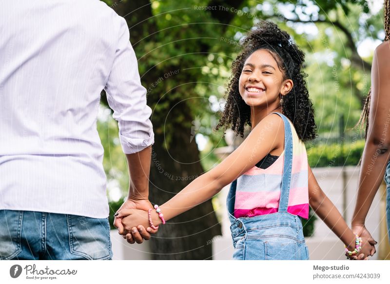 Little girl enjoying a walk outdoors with her parents. family together city street urban happy walking mother father daughter three day love cheerful happiness