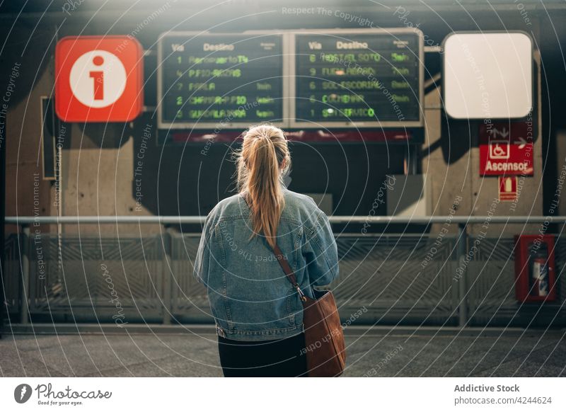 Woman on railway station with trains schedule woman departure board public urban passenger wait travel electronic arrive information passage metro direction