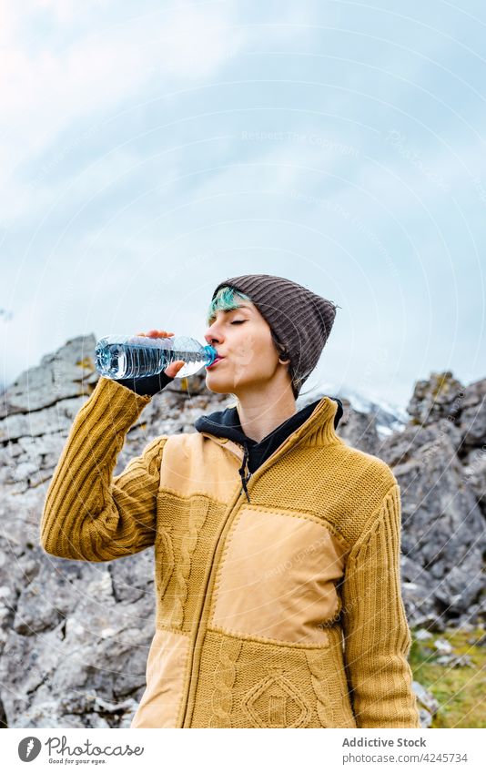 Traveling hiker with water bottle on high ridge traveler mountain valley drink achieve height nature tourist explore environment vacation adventure wanderlust