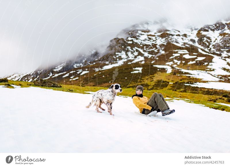 Woman sliding down snowy slope with dog woman mountain fun slide together run laugh valley pet nature animal winter cold activity canine happy peaks of europe