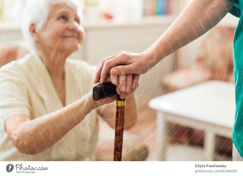 Nurse consoling her elderly patient by holding her hands people woman senior mature casual female Caucasian home house care health healthcare nursing home aging