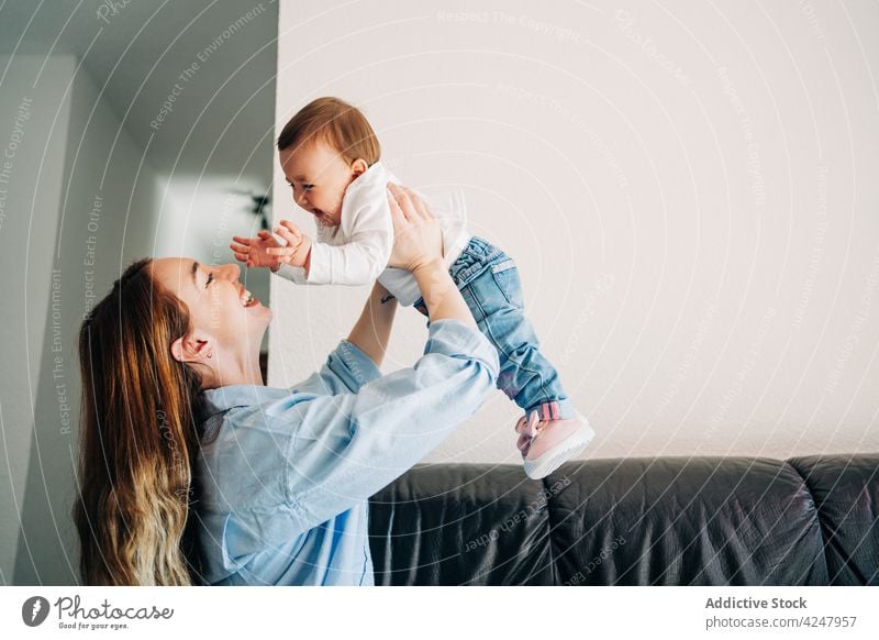 Joyful mother raising adorable baby on hands raise arms raised laugh together offspring care play having fun lift childcare joyful cheerful mom woman motherhood