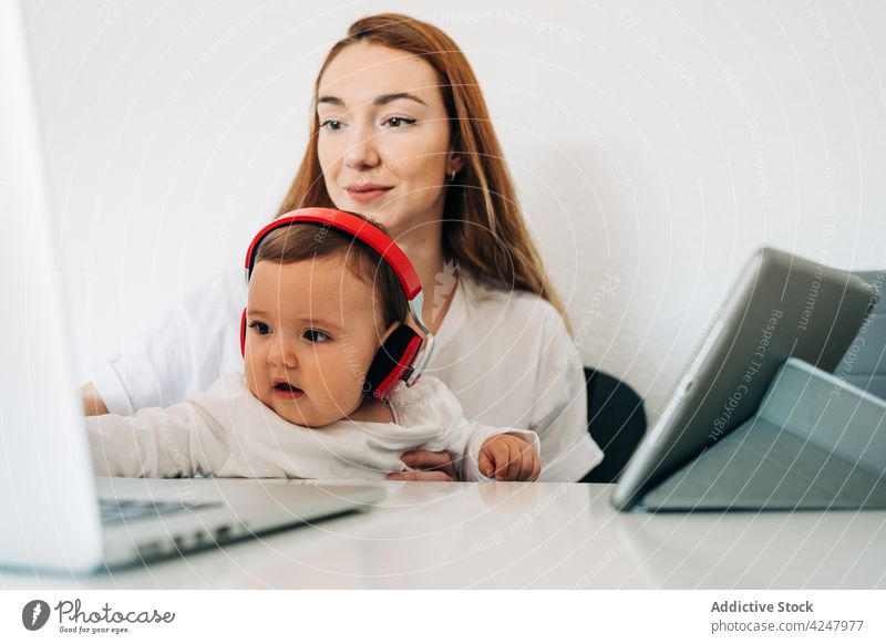 Mother and baby in headphone watching video on laptop mother headphones together attentive listen entertain interest curious computer at home woman motherhood