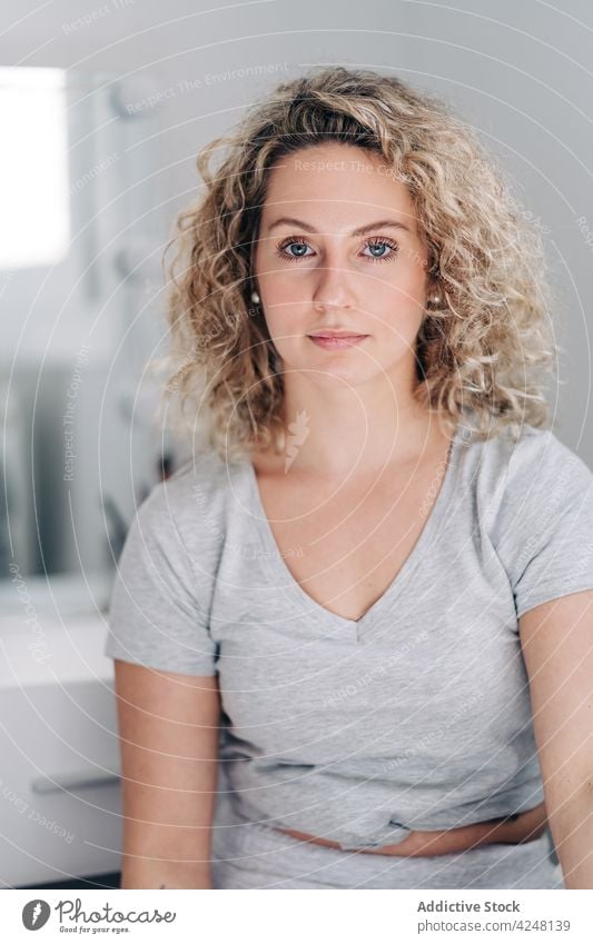 Attractive calm woman sitting in light room positive gorgeous curly hair appearance casual domestic sensitive young attractive pleasant optimist glad beautiful