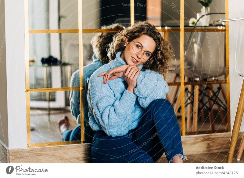 Self assured young woman sitting on floor and looking at camera style confident relax mirror feminine grace personality appearance individuality reflection