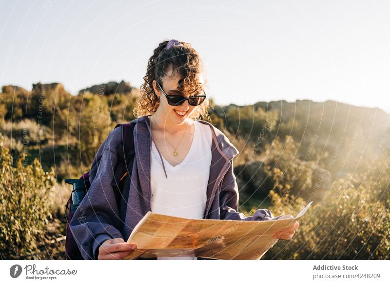 Trendy young woman walking in mountains with map in hands read adventure journey travel nature explore vacation traveler female brunette casual tourist location