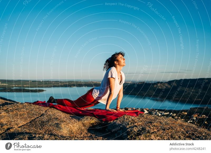 Active young woman performing Urdhva Mukha Svanasana yoga pose on rocky hill urdhva mukha svanasana cliff happy traveler admire mindfulness stretch