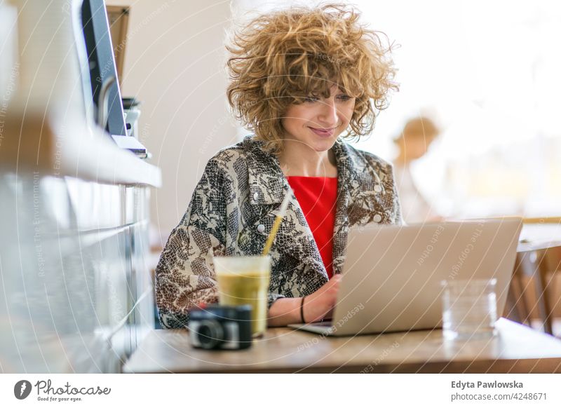 Young woman working on her laptop in cafe enjoying lifestyle young adult people one person casual caucasian positive carefree happy smile smiling female